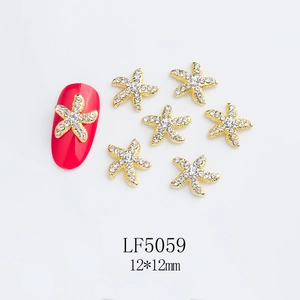 Macro view of 12x12mm golden alloy starfish nail charms with rhinestones on red nail