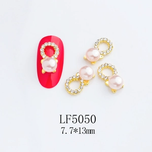 Detail of pink pearl nail jewelry charm with gold frame and crystals on a red nail