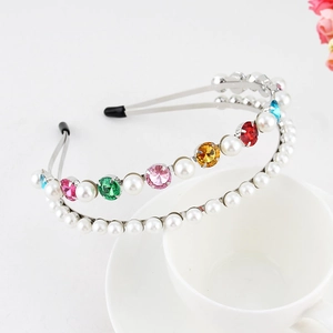 Detail of double-layer silver headband with colorful gemstones and pearls on a white cup