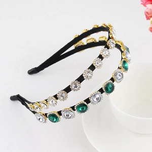 Detail shot of baroque style headband featuring emerald green rhinestones and golden base