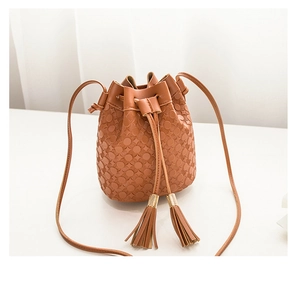 Détail du sac seau marron caramel avec gaufrage géométrique et pompons en cuir