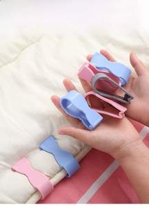 Close-up of bow-shaped duvet clips in pink and blue on a soft white bedding surface