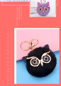 Detail of owl faux fur pompom keychains featuring gold-toned eyes and glitter ears