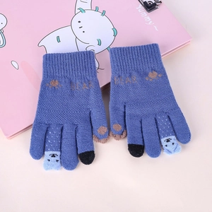 Détail d'un gant d'hiver en tricot bleu avec texte BEAR et bouts de doigts tactiles sur rose