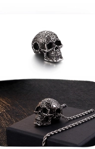 Vue détaillée du pendentif tête de mort vintage avec gravures et chaîne torsadée