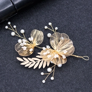 Elegant gold flower bridal headpiece with white pearls and leaves on a dark backdrop