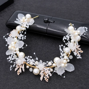 Close-up of bridal headband with white pearls, frosted flower petals and golden leaves