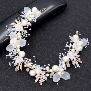 Close-up of bridal headband with gold leaves, pearls, and flowers on black background