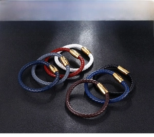 Dettaglio di bracciali in pelle intrecciata con chiusure magnetiche dorate colori