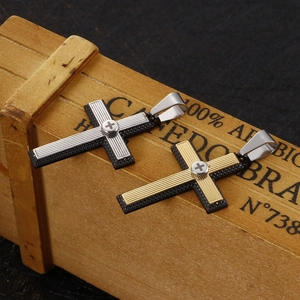 Two-tone stainless steel cross pendant necklaces in silver and gold on a vintage box