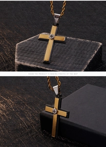 Detail of two-tone stainless steel cross pendant with textured finish and gold rope chain