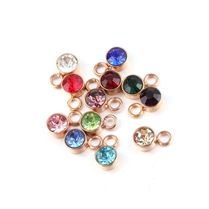 Rose gold stainless steel birthstone charms with faceted crystals on white background