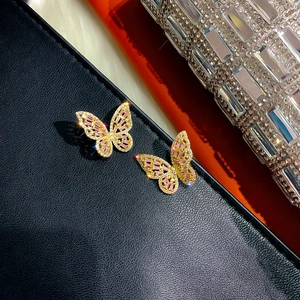 Macro detail of butterfly earrings with pink and white zircons on black leather