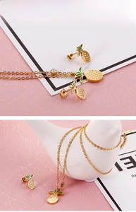 Detail of gold pineapple jewelry set featuring fine steel necklace and crystal earrings
