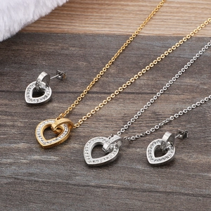 Gold and silver heart jewelry set with necklace and stud earrings on wooden surface