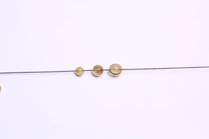Close-up of 14k gold-plated circular beads with crystal inlays on a fine dark jewelry cord