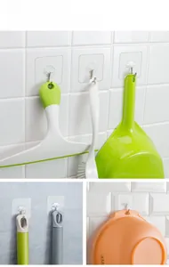 Strong adhesive wall hooks holding household cleaning tools on white tile surface