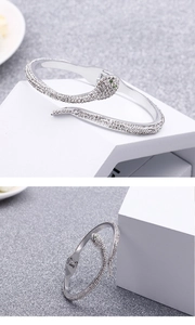 Detail of silver snake bracelet with white crystals and green zircon eyes on white blocks
