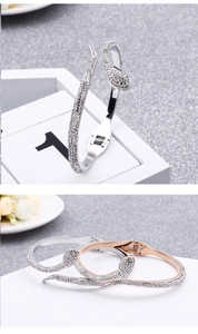 Detail of snake-shaped open bracelets in silver and rose gold with sparkling zircon stones
