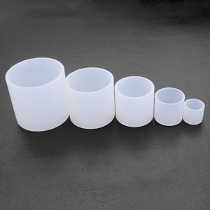 Five translucent white silicone cylinder molds in various sizes on black leather texture