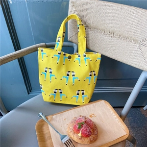 Detail of yellow canvas lunch bag featuring creative figures and premium snap button