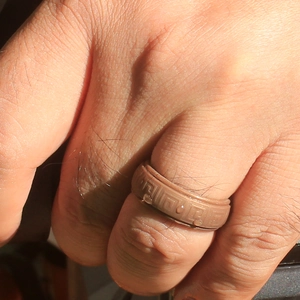 Macro shot of brown silicone ring with Greek key pattern and water drops on skin