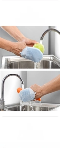 Blue silicone cleaning gloves scrubbing fresh fruit in a kitchen sink with water