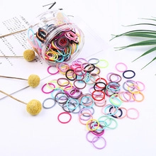 Close-up of colorful mini elastic hair bands spilling from a clear jar with dried flowers