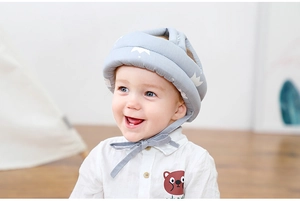 Close-up of light grey baby safety helmet with crown pattern and adjustable straps