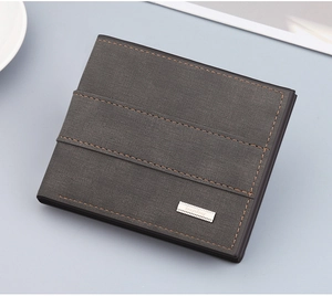 Detail of dark grey frosted leather wallet with brown stitching and metal logo plate
