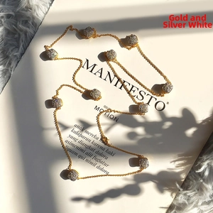 Close-up of long gold chain necklace featuring multiple square pavé diamond pendants