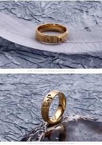 Close-up of golden stainless steel men's ring featuring DAD embossed text on a wide band