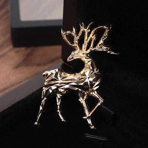 Macro shot of 3D geometric gold deer brooch resting in a black velvet jewelry gift box