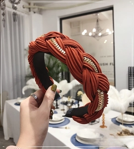 Dettaglio della fascia intrecciata arancione con catena in metallo dorato decorativa