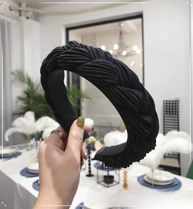 Detail of a wide black braided headband showing elegant fabric texture and twist design
