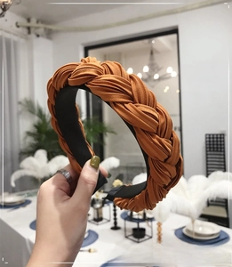 Detail shot of orange pleated fabric braided headband showing textured woven structure