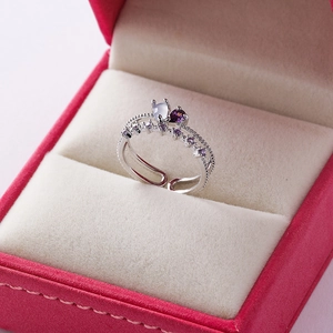 Detailed close-up of a silver floral ring with blue and purple gemstones in a gift box