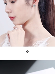 Close-up detail of silver heart stud earrings with sparkling pavé zircons on model