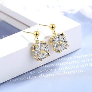 Sparkling gold snowflake drop earrings with square zircon crystals on a white pedestal