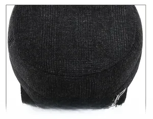 Detail of meticulous stitching on the top of a grey plaid wool winter hat for men