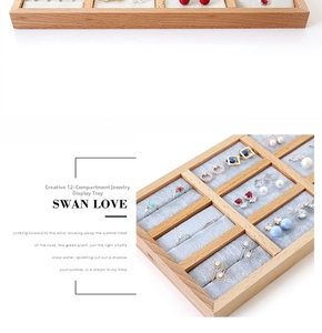 Close-up of a 12-slot beech wood jewelry display tray with soft grey velvet lining