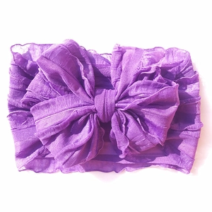 Detail of purple infant headband featuring a large bow and soft pleated texture fabric