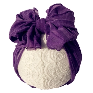 Detail of a deep purple baby headband featuring a large layered lace mesh bow