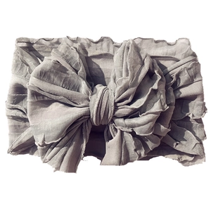 Close-up of a grey layered lace bow headband for babies with delicate pleated fabric texture
