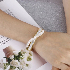 Elegant gold-plated bangle featuring rows of white pearls and shimmering rhinestones