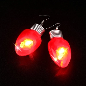 Macro shot of creative red LED light bulb Christmas earrings glowing against black backdrop
