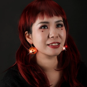 Close-up of glowing LED pumpkin earrings with red light for Halloween party style