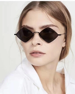 Detail of geometric rhombus sunglasses with black metal frames and dark lenses on model