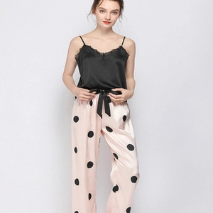 Détail de caraco en satin noir avec dentelle et pantalon rose à pois avec nœud décoratif