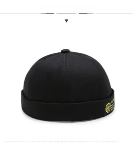 Close-up of black cotton miki hat with yellow round badge and side embroidery detail